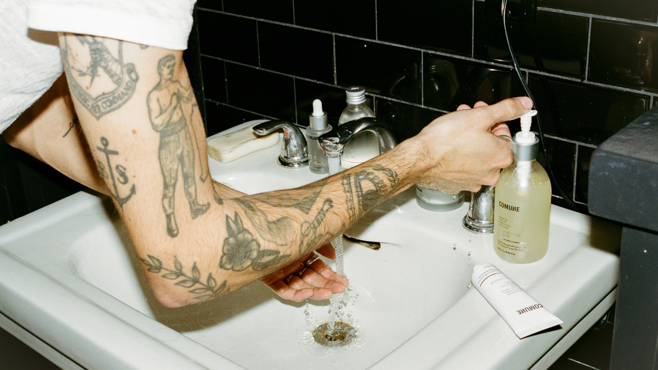 COMUNE Arist Brandon getting ready to clean his face with COMUNE Essentials Face Cleanser in the bathroom sink.