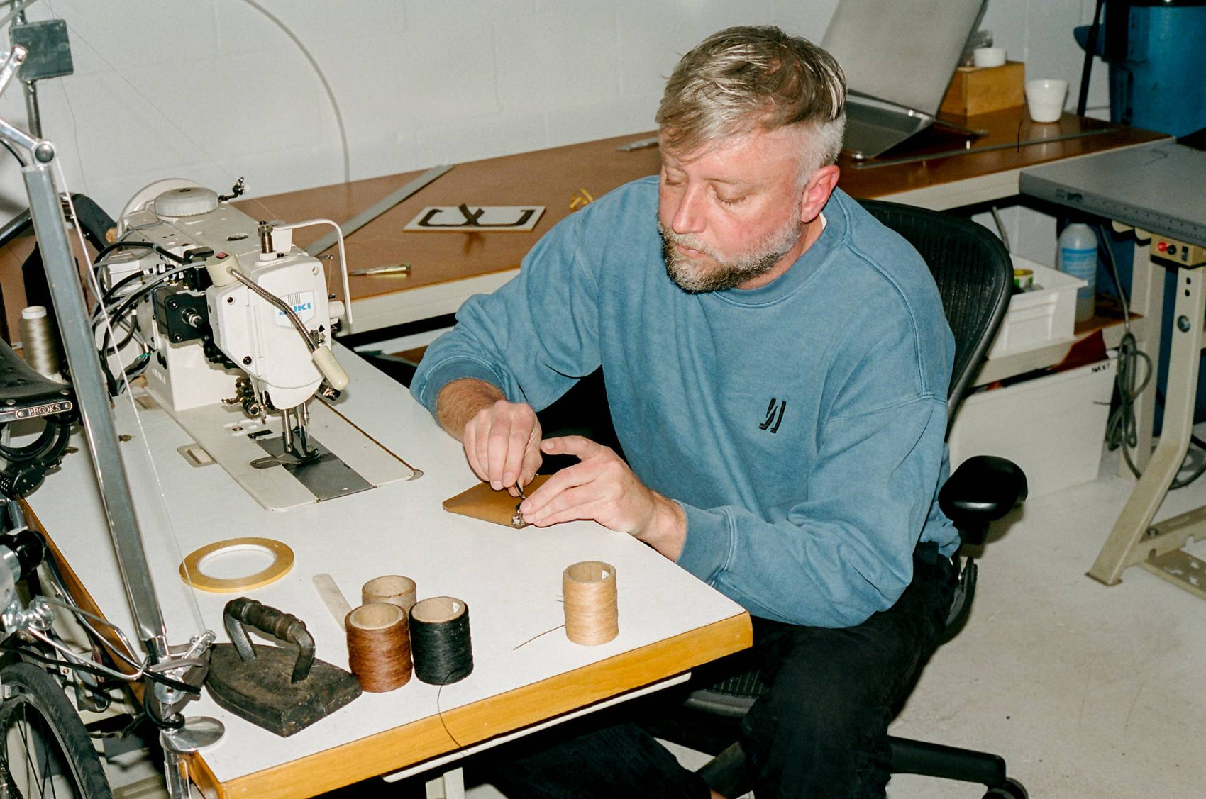 COMUNE artist Jason Gregory from MAKR working on a sewing machine in a workshop setting