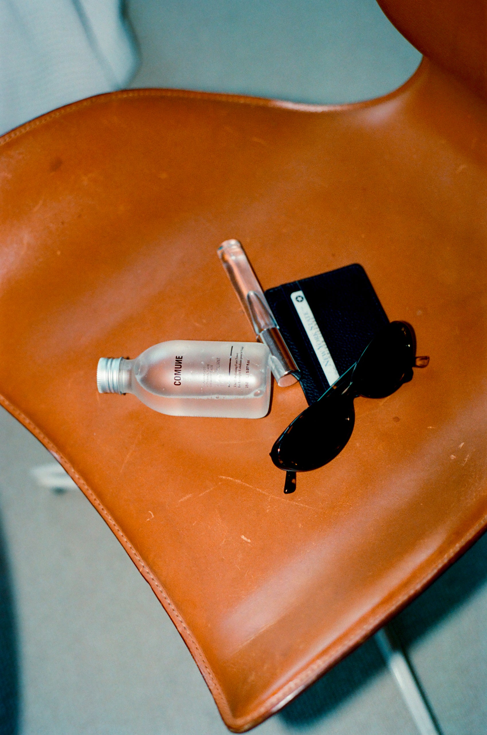 Comune AHA Exfoliant Toner on top of leather chair with other items