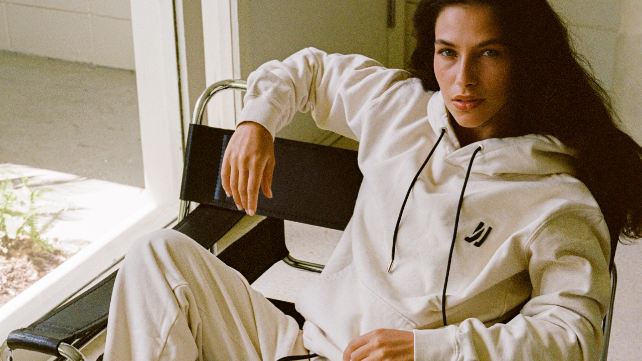 Women wearing COMUNE clothing sitting on a black leather chair in her living room.