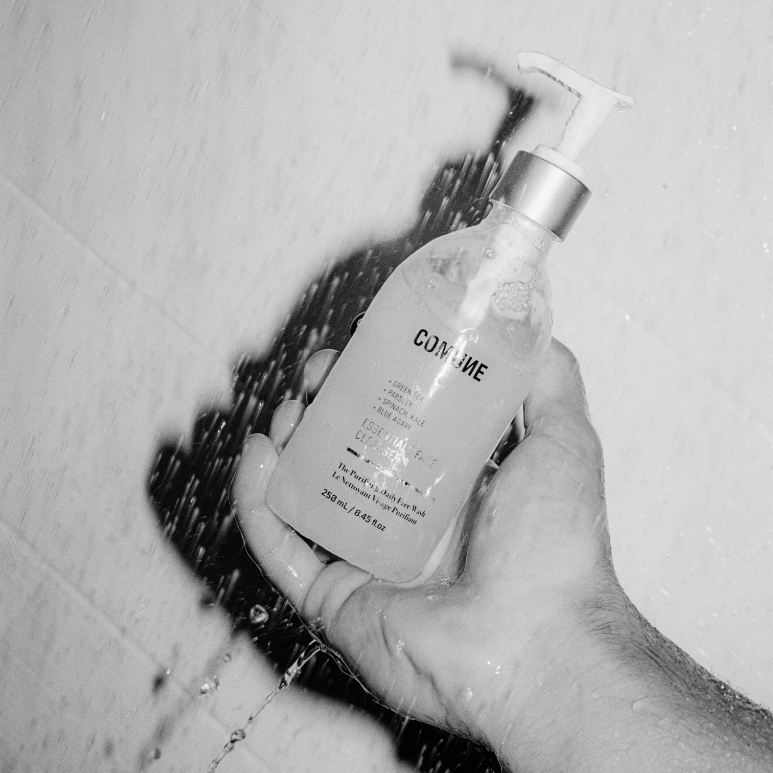 A hand holding COMUNE Essentials Face Cleanser