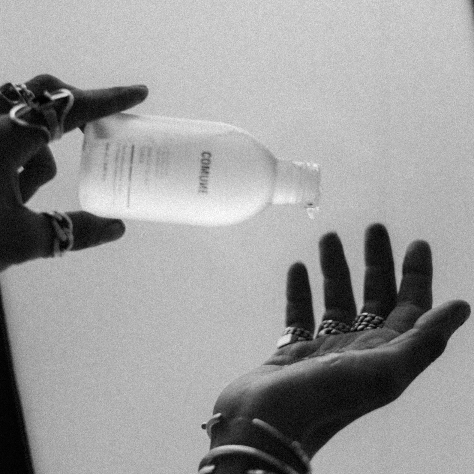 COMUNE AHA Exfoliant Toner held by one hand while dripping on to the other hand of a person