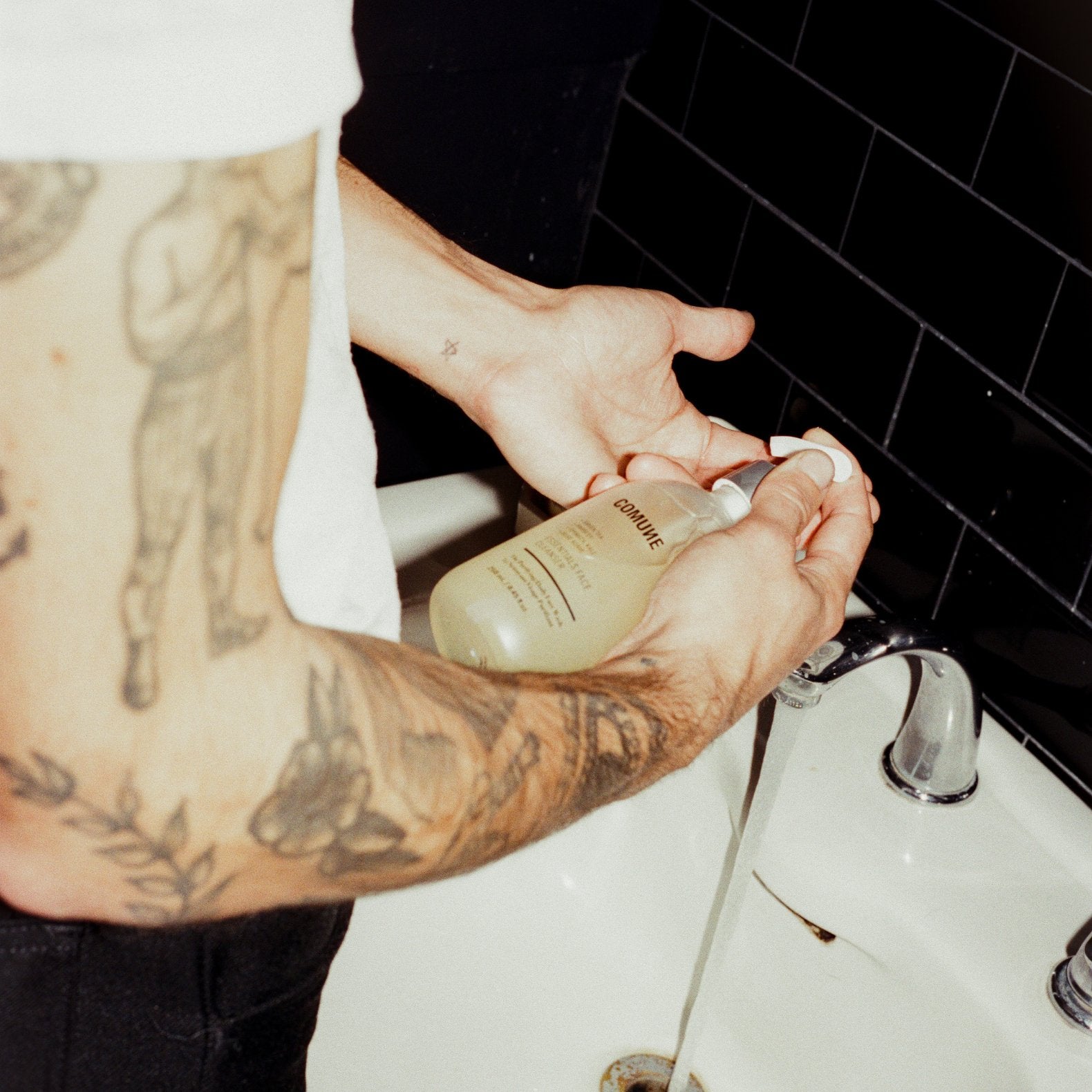 Male holding Comune Essentials Face Cleanser