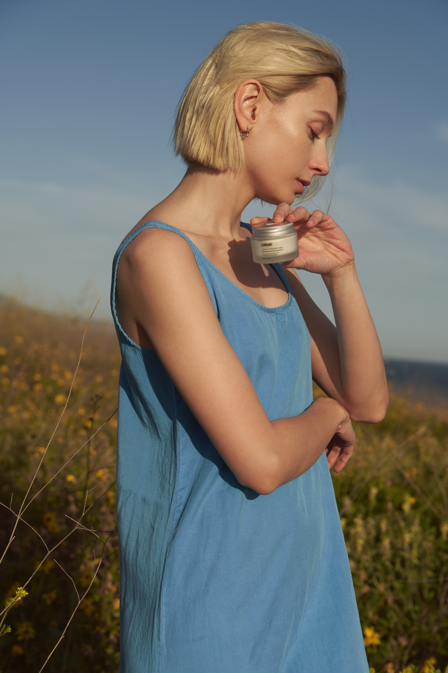 Comune Revitalize Overnight Mask held by a women in the flower fields