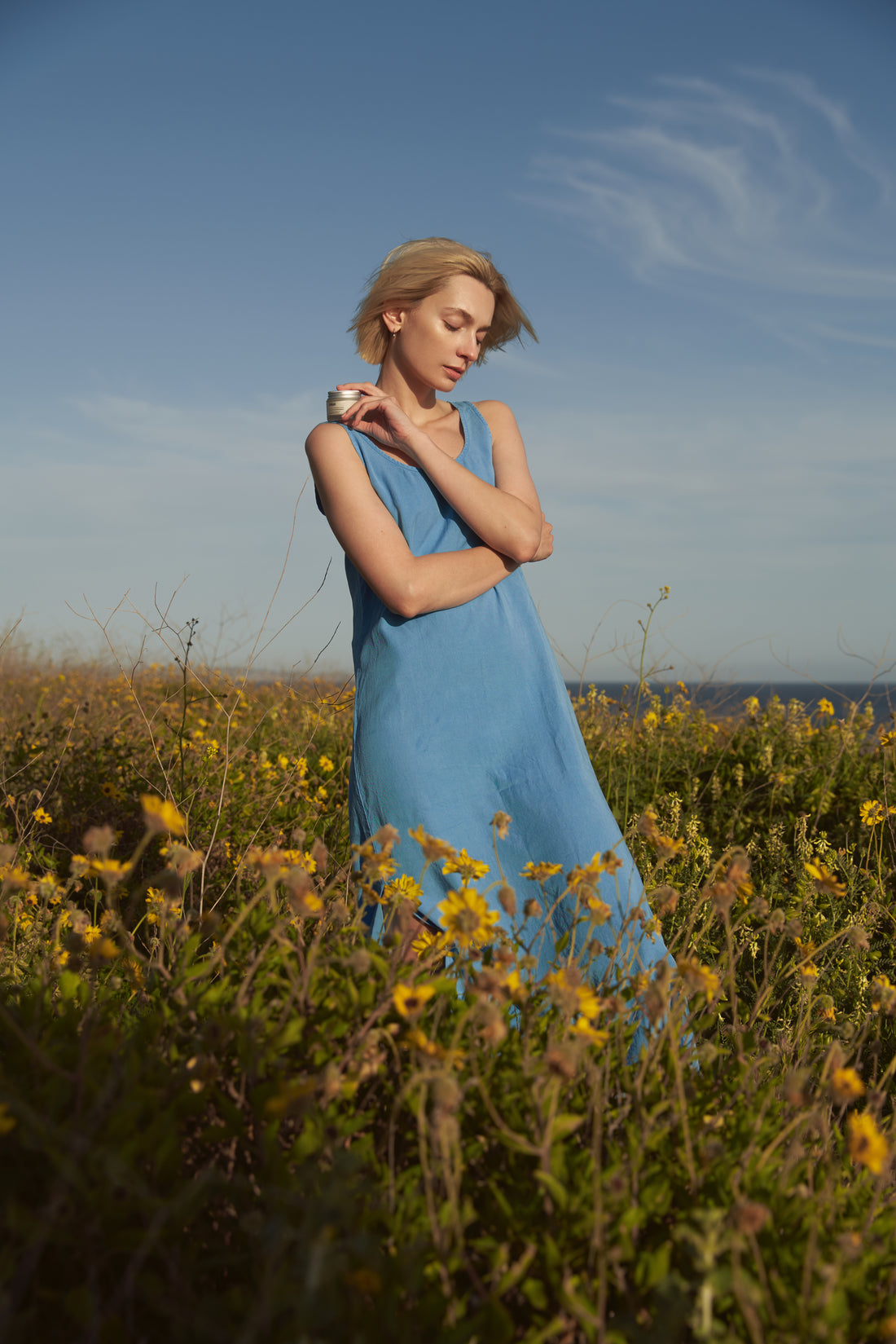 Comune Revitalize Overnight Mask held by a women in the flower fields near the ocean