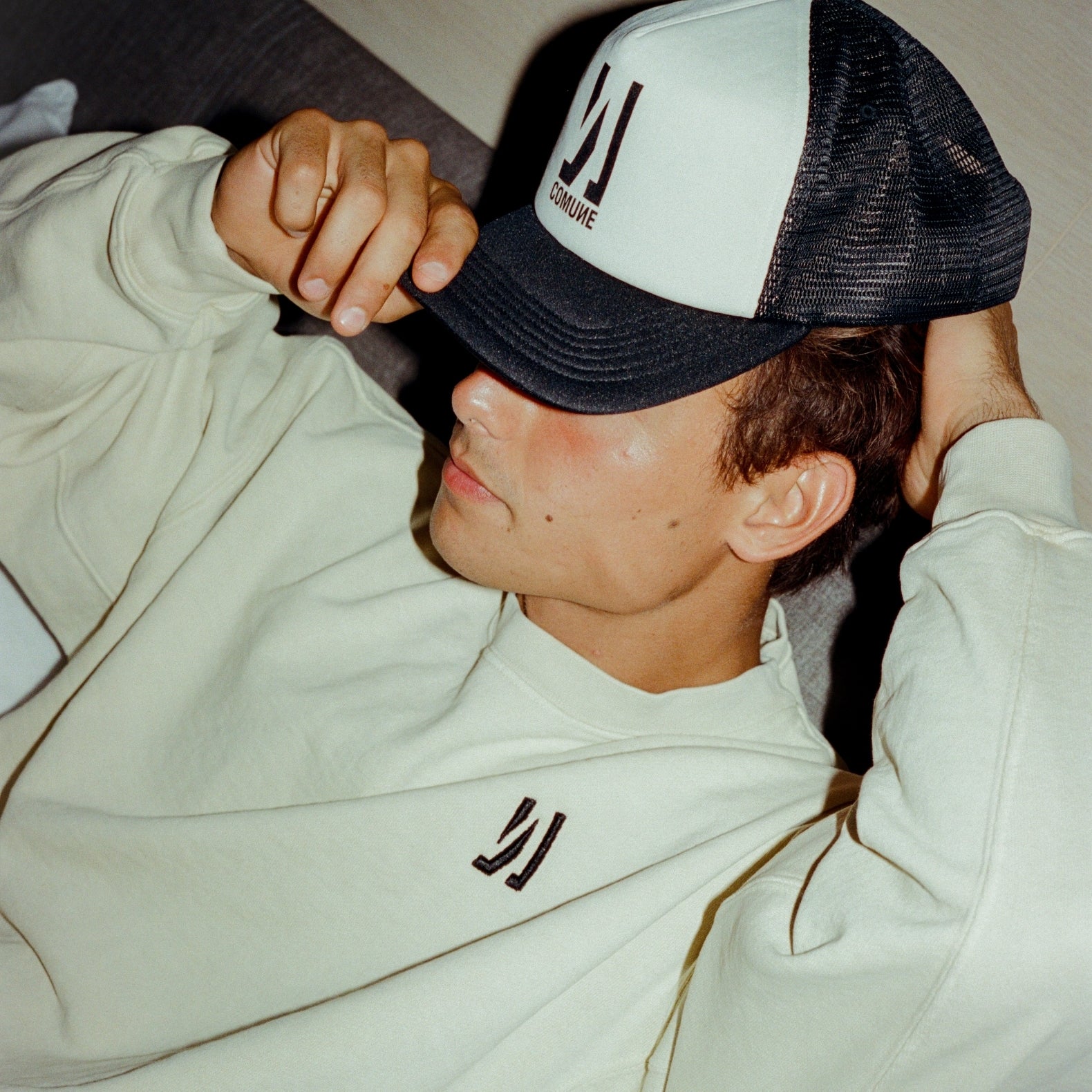 Person wearing a COMUNE cap and Comune Duke Crew Sweatshir with a 'COMUNE' brand logo.