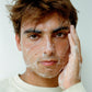 Surfer applying Comune Essentials Face Cleanser on his face to cleanse surface impurities while revitalizing to help reveal clearer, healthier-looking skin