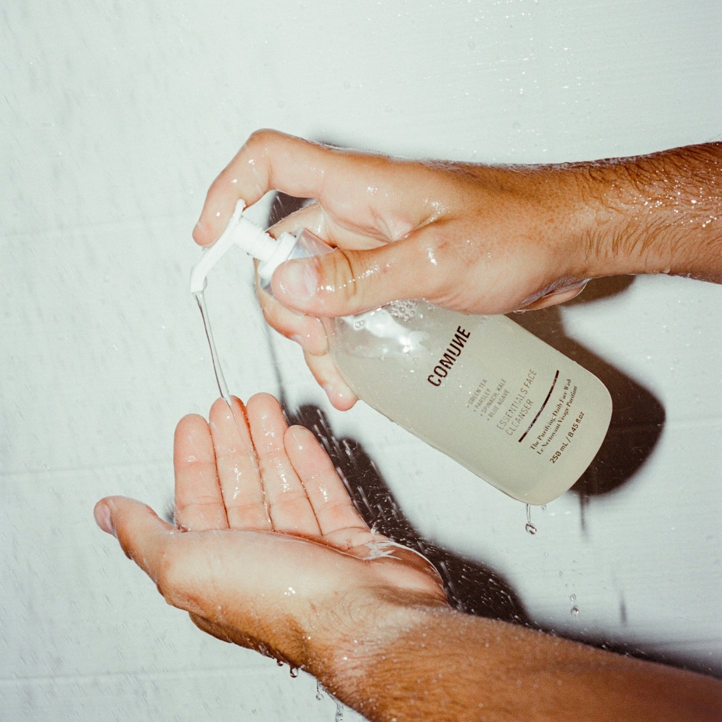 Applying Comune Essentials Face Cleanser that gently cleanses without drying or stripping