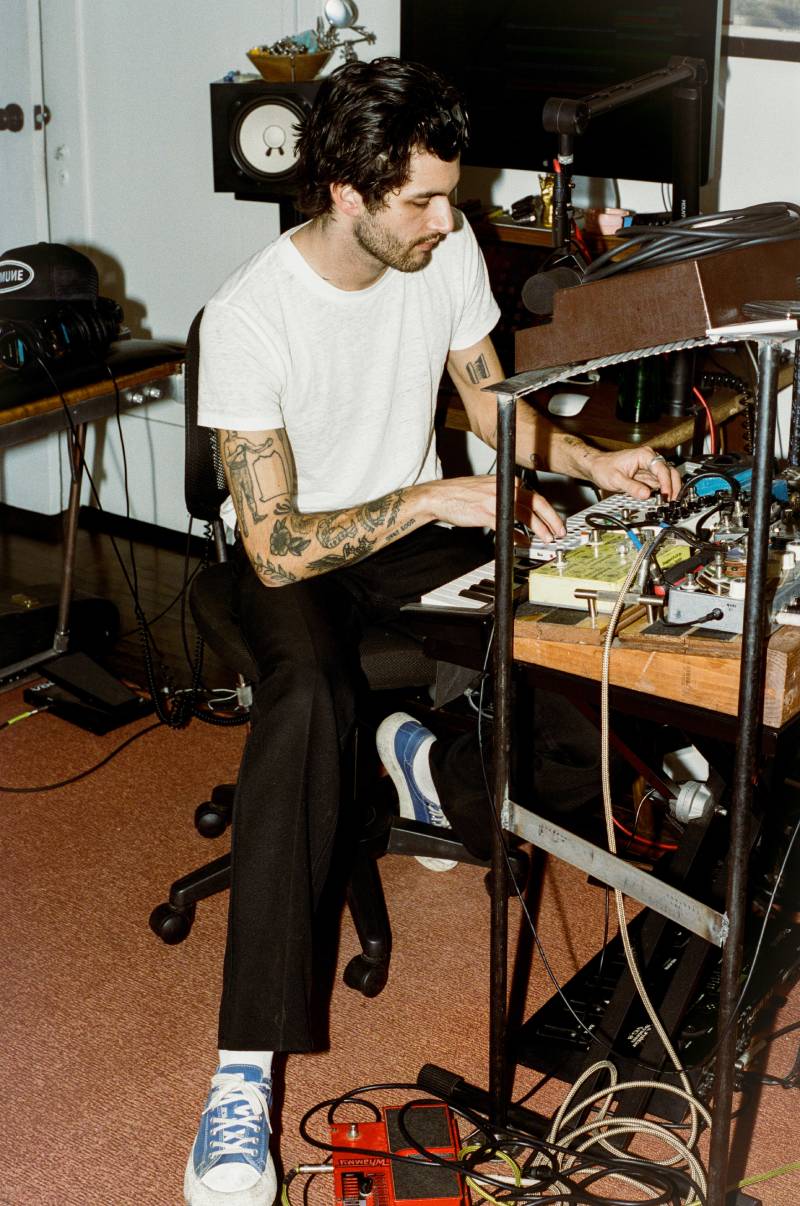 Man with tattoos working on electronic equipment in a studio setting