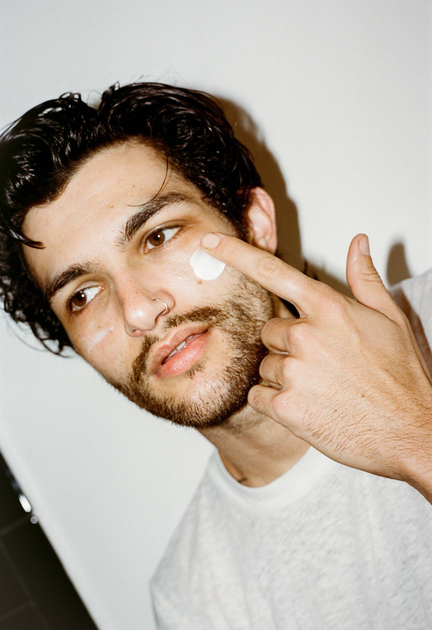 Man applying cream to his face with a white background