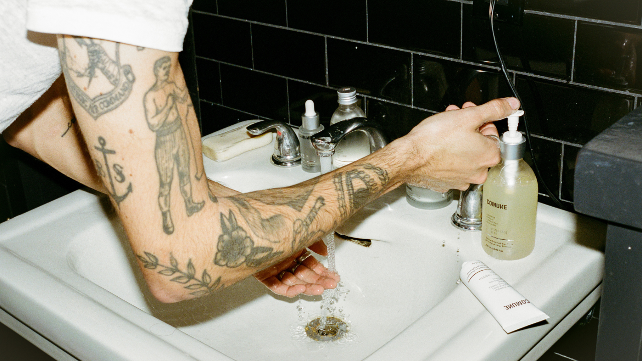 Comune model gettting ready to apply 'COMUNE' Essentials Face Cleanser in the bathroom