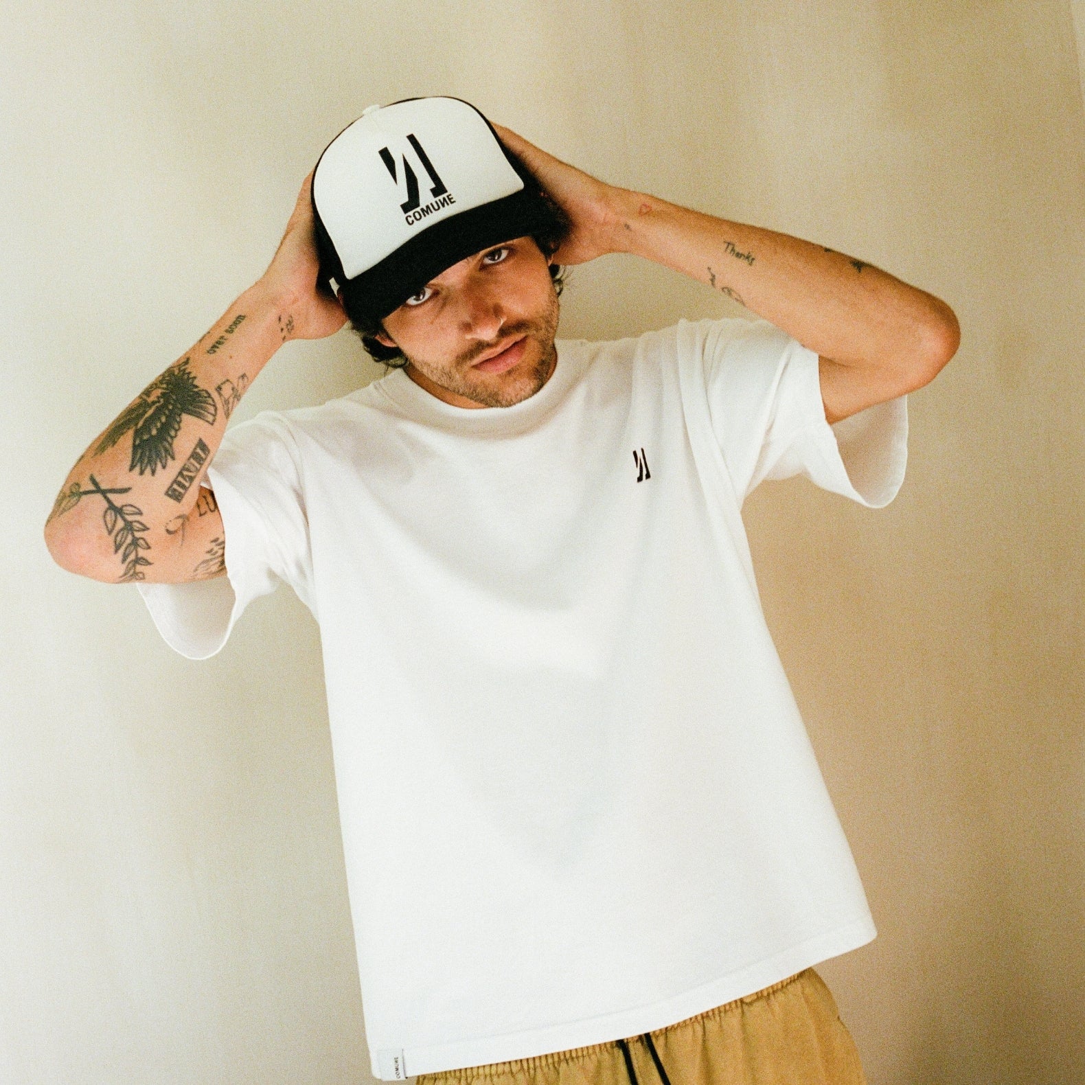 Men wearing COMUNE trucker hat with Ryder oversized tee on natural background. COMUNE Ryder Oversized Tee | White
