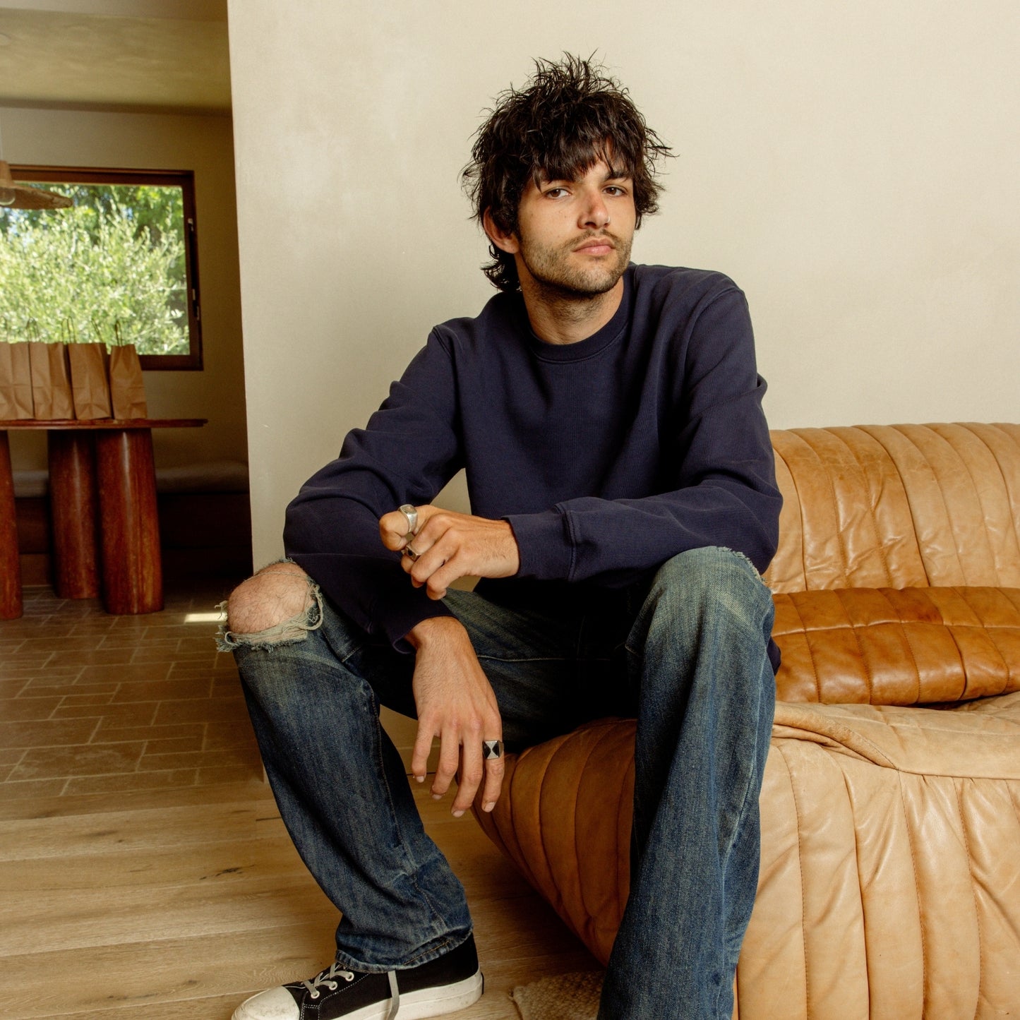 Person wearing the Luka Crew heavyweight cotton sweater in navy color sitting on a sofa in the living room. COMUNE Luka Crew | Navy