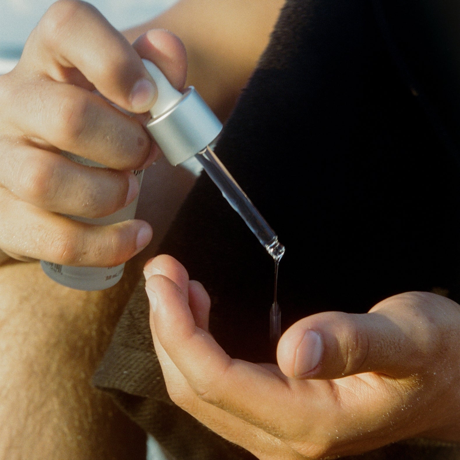 Person using a dropper to apply COMUNE Vita boost Serum to their skin