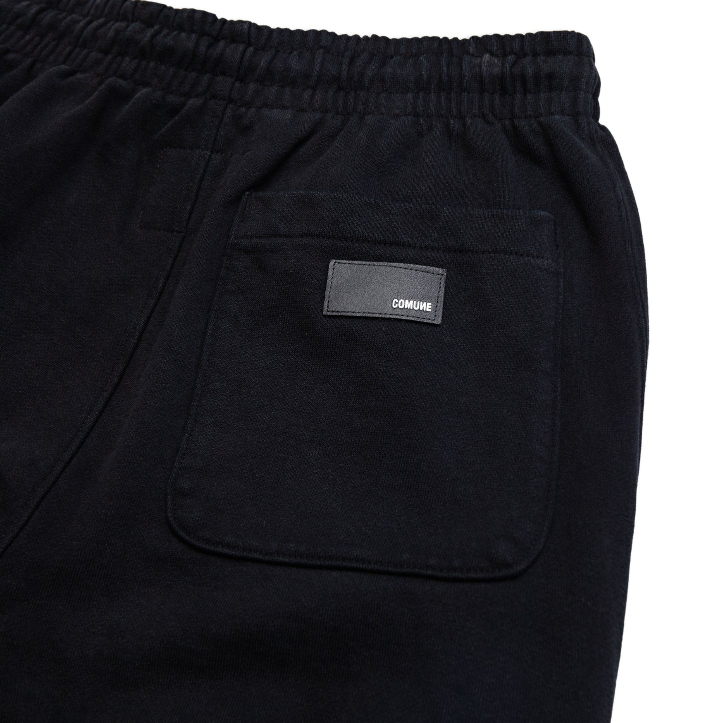 Comune Duke Sweatpants in heavyweight cotton with side gusset in black color on white background, leather patch close up. COMUNE DUKE SWEATPANTS | Black