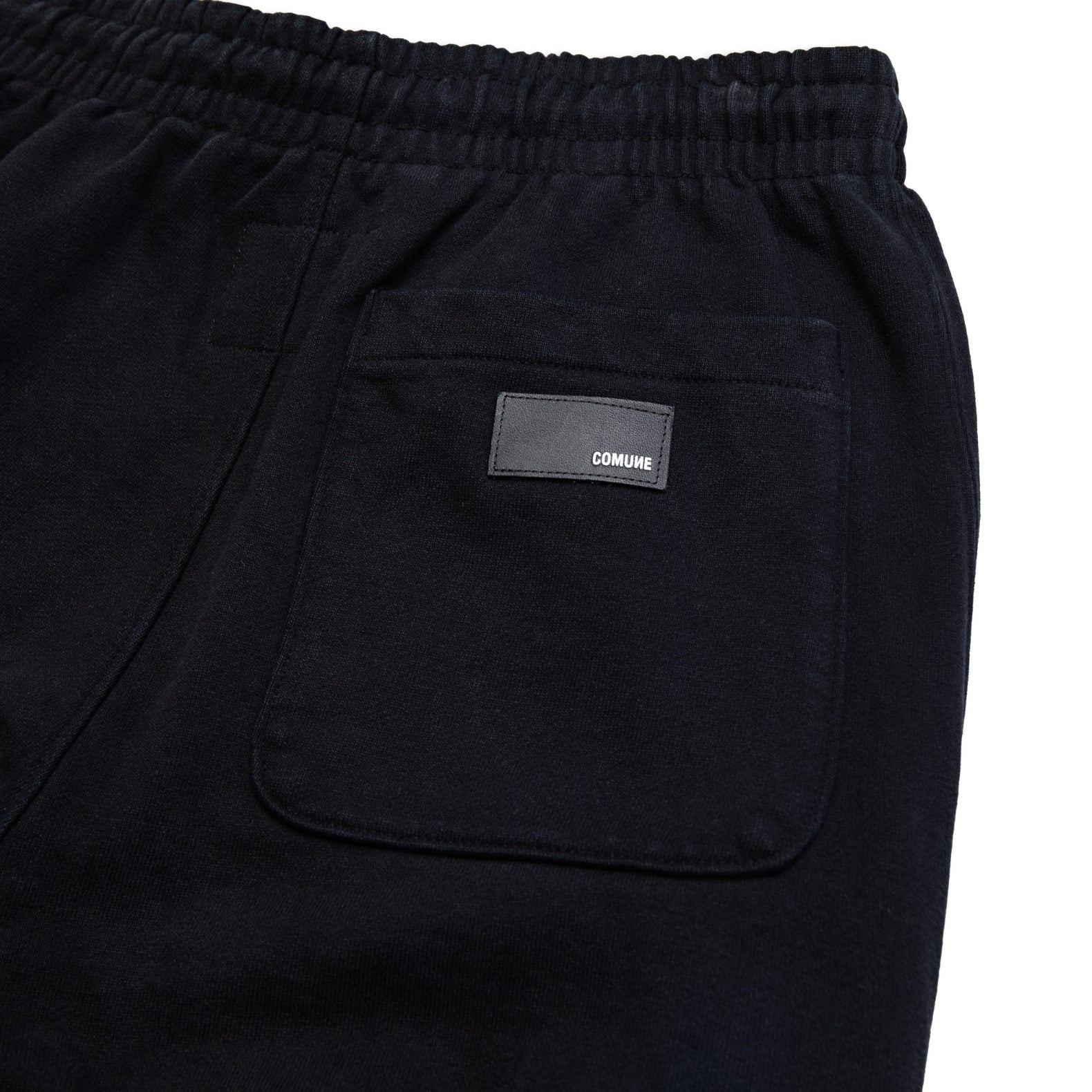 Comune Duke Sweatpants in heavyweight cotton with side gusset in black color on white background, leather patch close up. COMUNE DUKE SWEATPANTS | Black