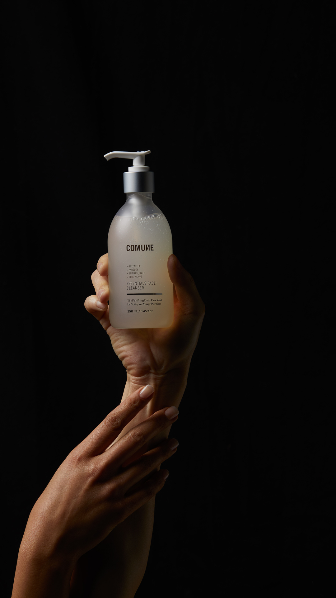 Comune Essentials Face Cleanser held by a man and women