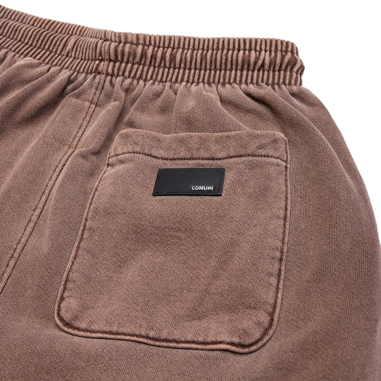 Comune Enzo Joggers heavyweight cotton in brown color on white background, leather patch close up. COMUNE ENZO JOGGER | Brown