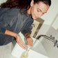 COMUNE model applying comune essentials face cleanser  in a bathroom