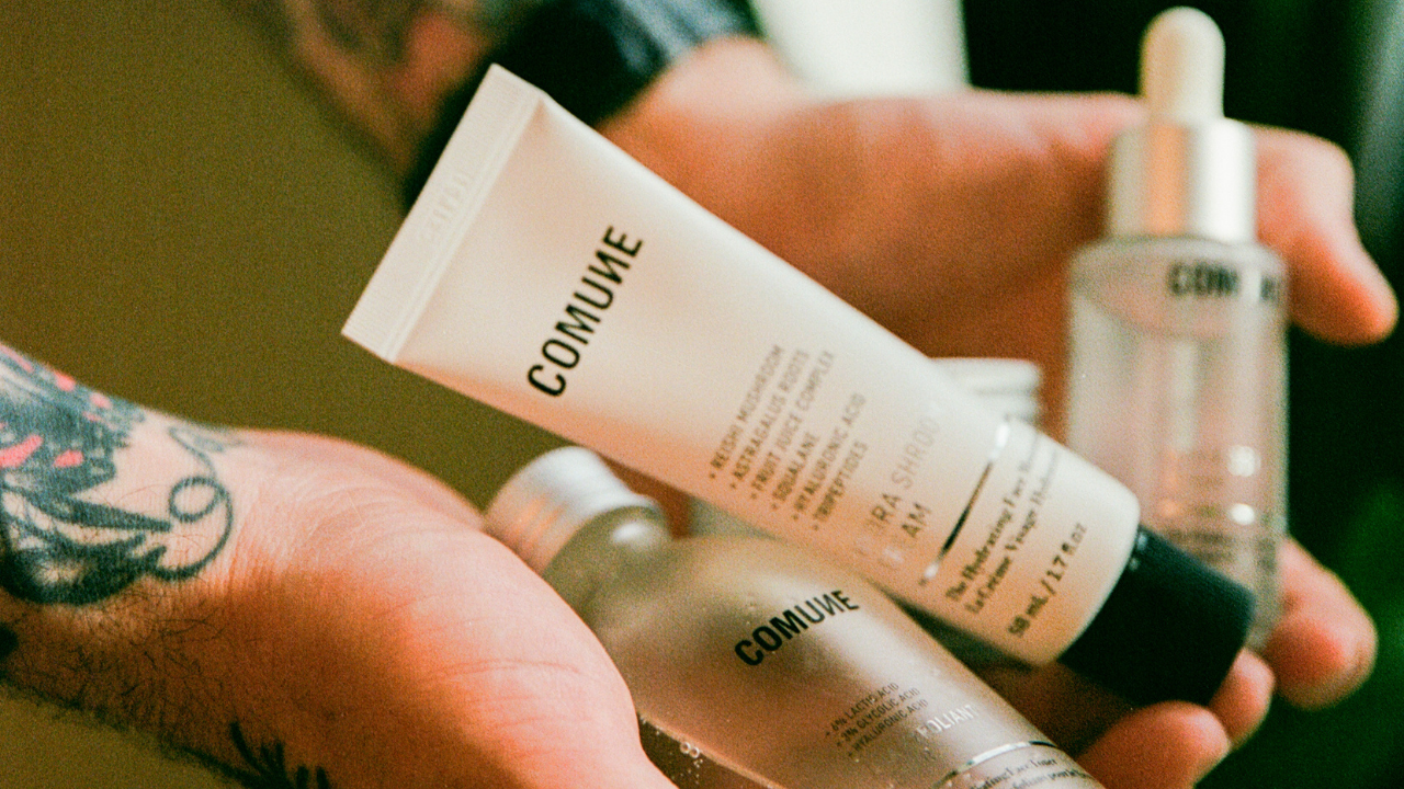 Hand holding skincare products with 'COMUNE' branding.