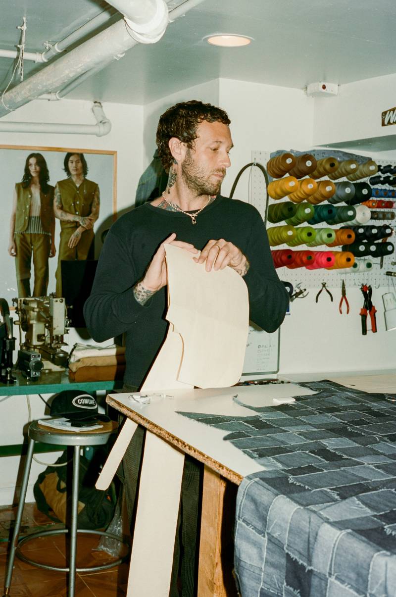 COMUNE artist Jackson Owens working on a denim patterns in a workshop with tools and equipment in the background.