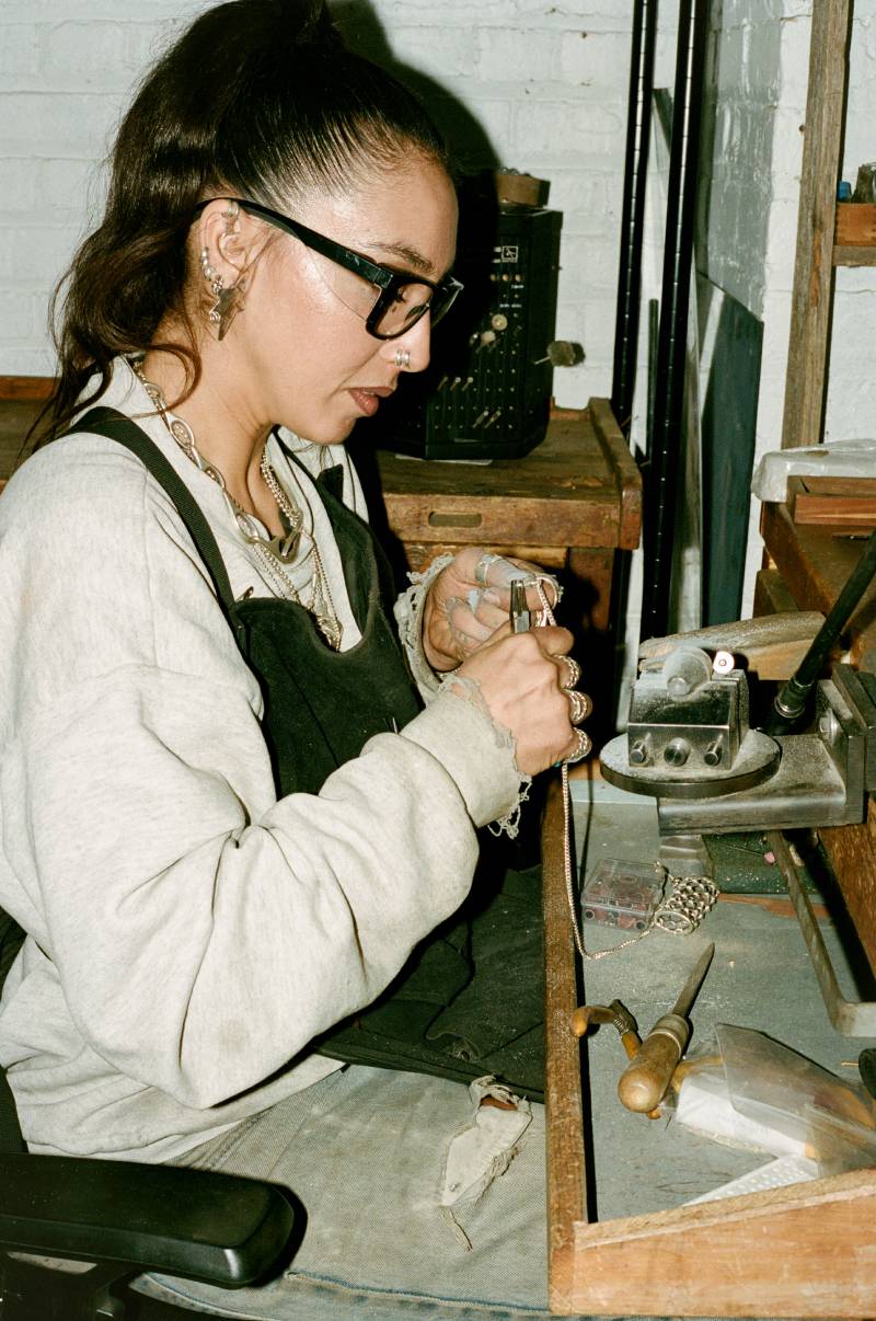 COMUNE artist Lizz Jardim working at a work bench working on jewelry designed set.