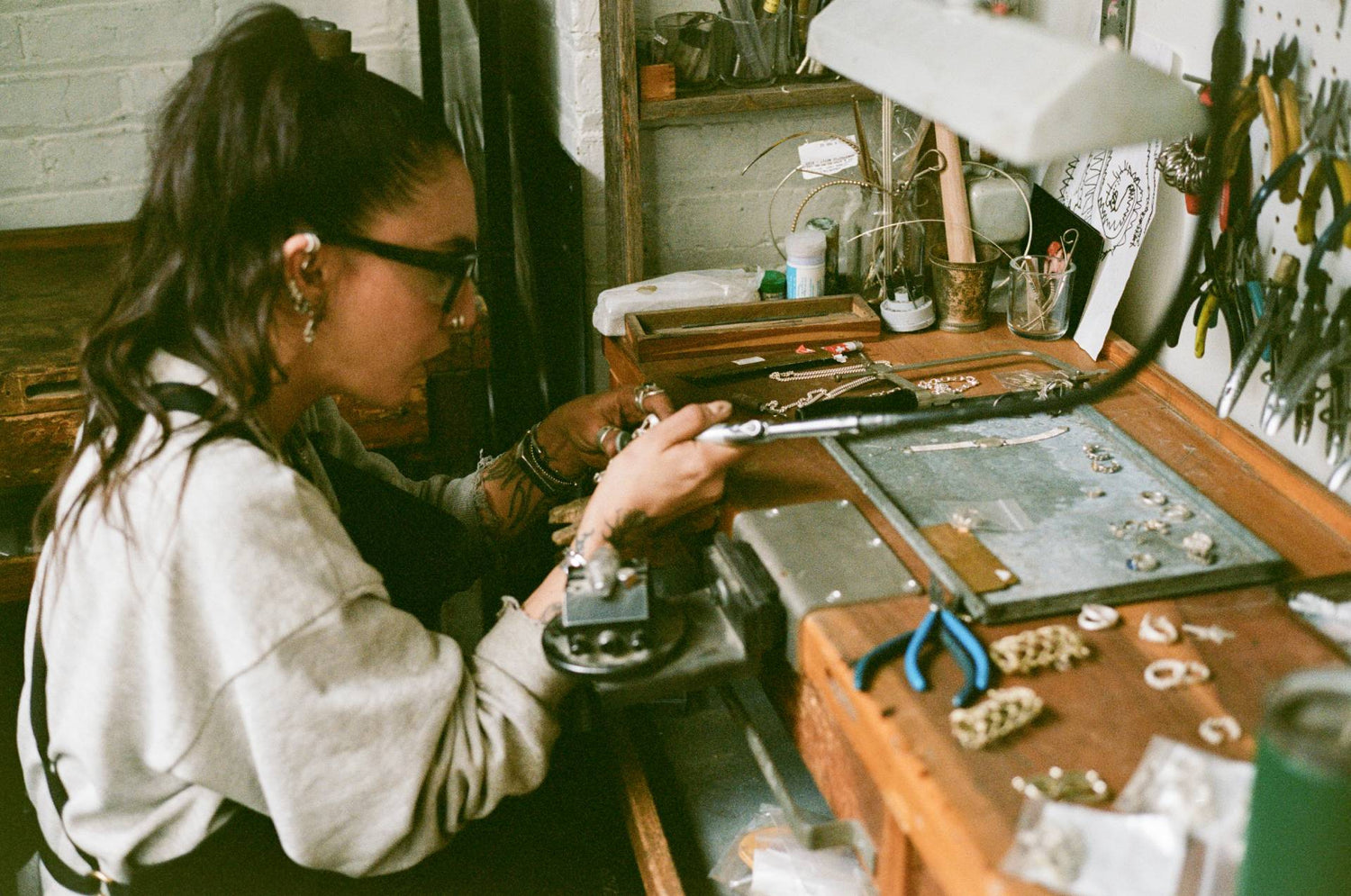 Person working at a jewelry-making station with tools and materials.