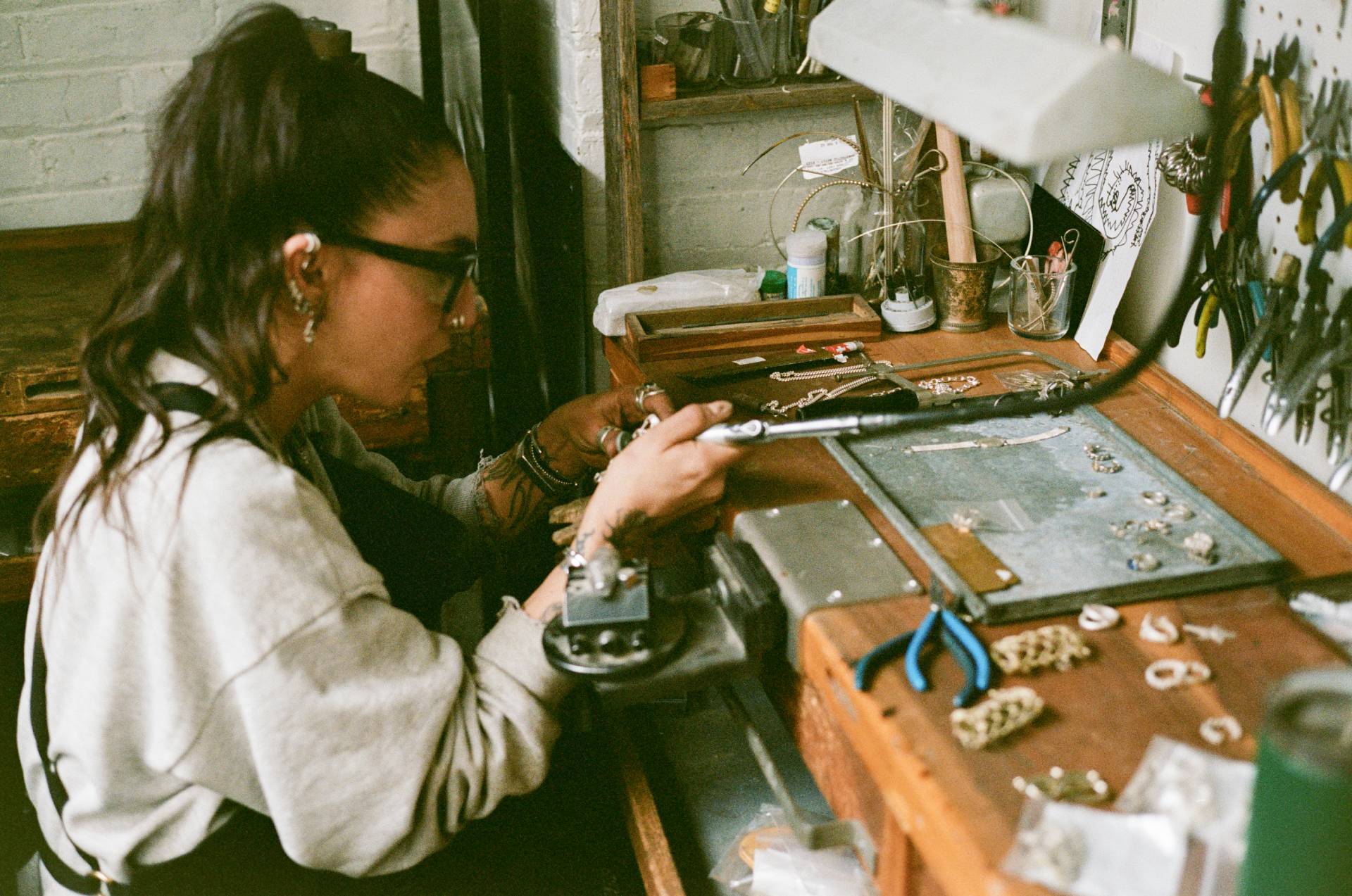 COMUNE artist Lizz Jardim working at a jewelry-making station with tools and materials.