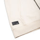 Comune Luka Zip-up in heavyweight cotton hoodie in bone color on white background, leather logo close up. COMUNE LUKA ZIP-UP | Bone
