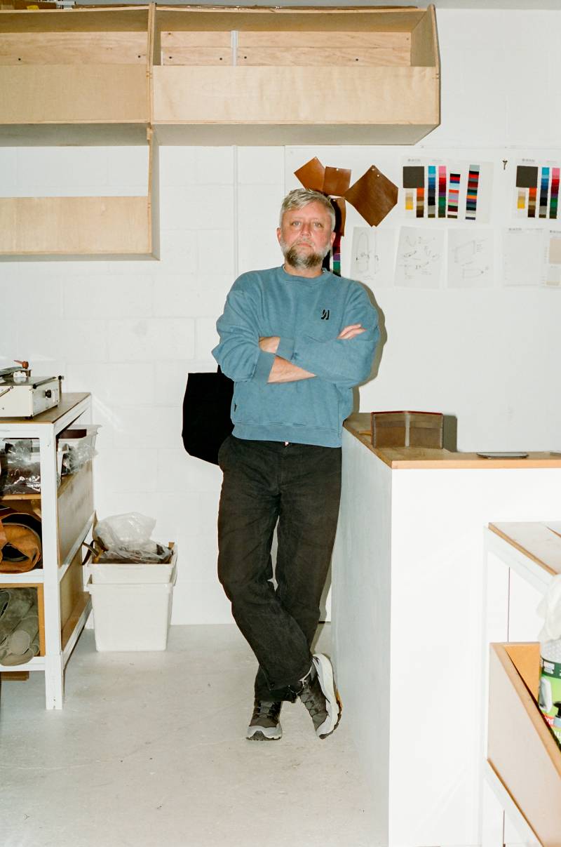 COMUNE artist Jason Gregory from MAKR standing in a room with white walls and wooden furniture