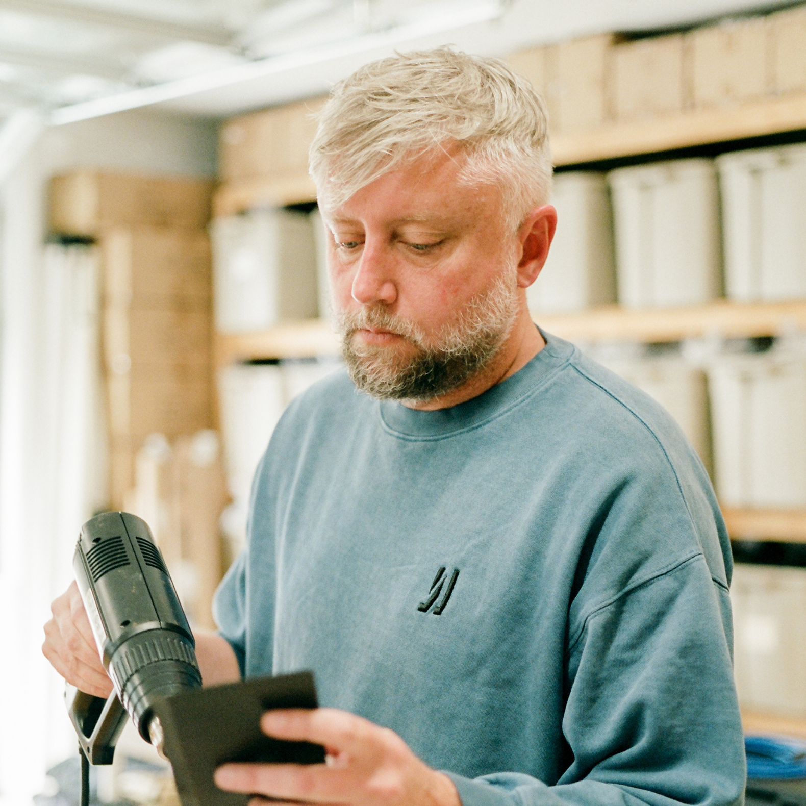 COMUNE artist Jason Gregory from MARK holding heat gun and applying glue to  a leather wallet.