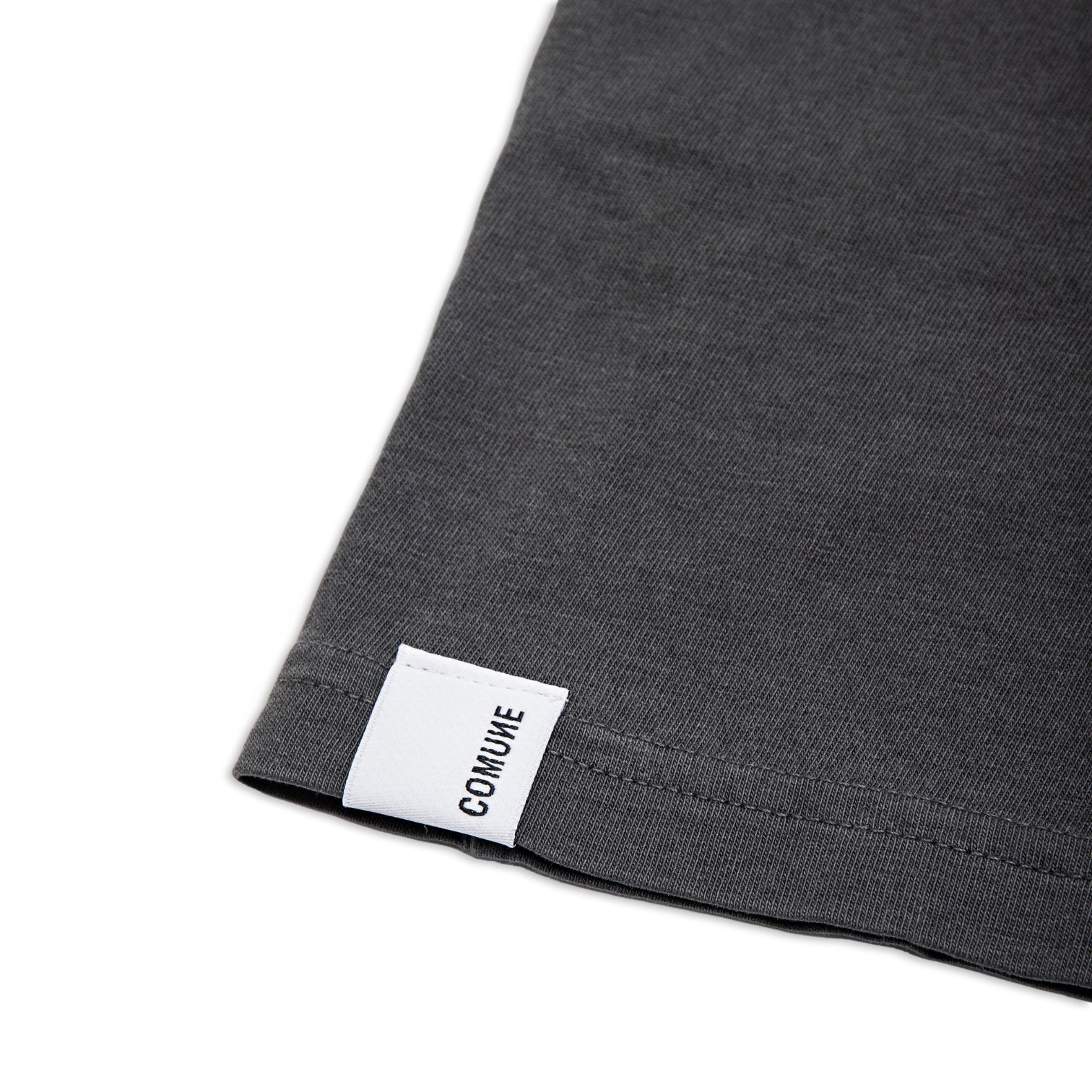 Comune Ryder tee in soft 100% cotton in faded black color on white background, label and hem close up. COMUNE RYDER TEE | Faded Black