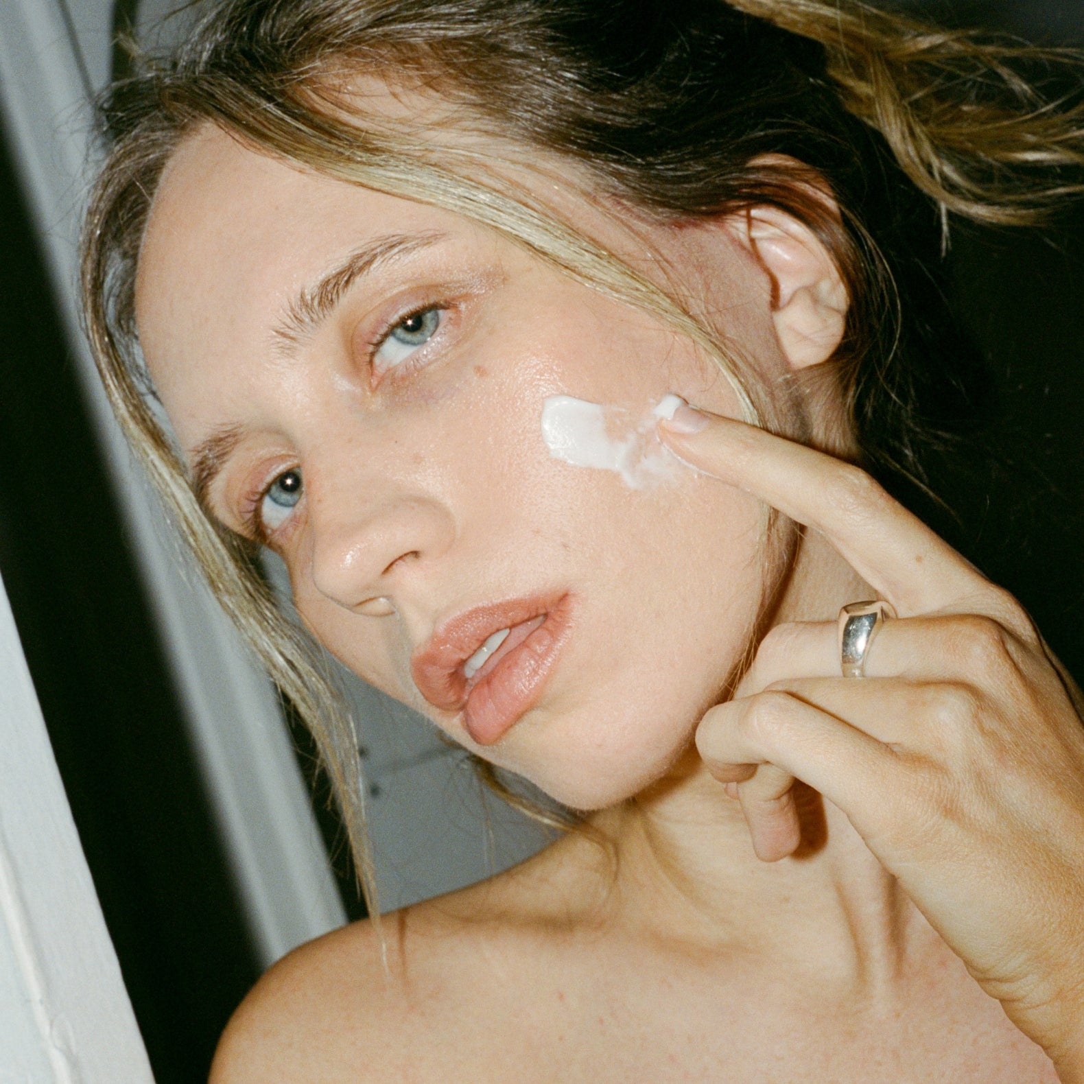 Woman applying cream to her face with a blurred background