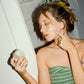 Woman applying 'COMUNE' Revitalize Overnight Mask as dual night cream to her face in front of a mirror