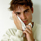Man wiping his face with a white towel against a plain background