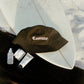 COMUNE essentials skincare along with comune's black bucket hat on a surfboard on the beach.