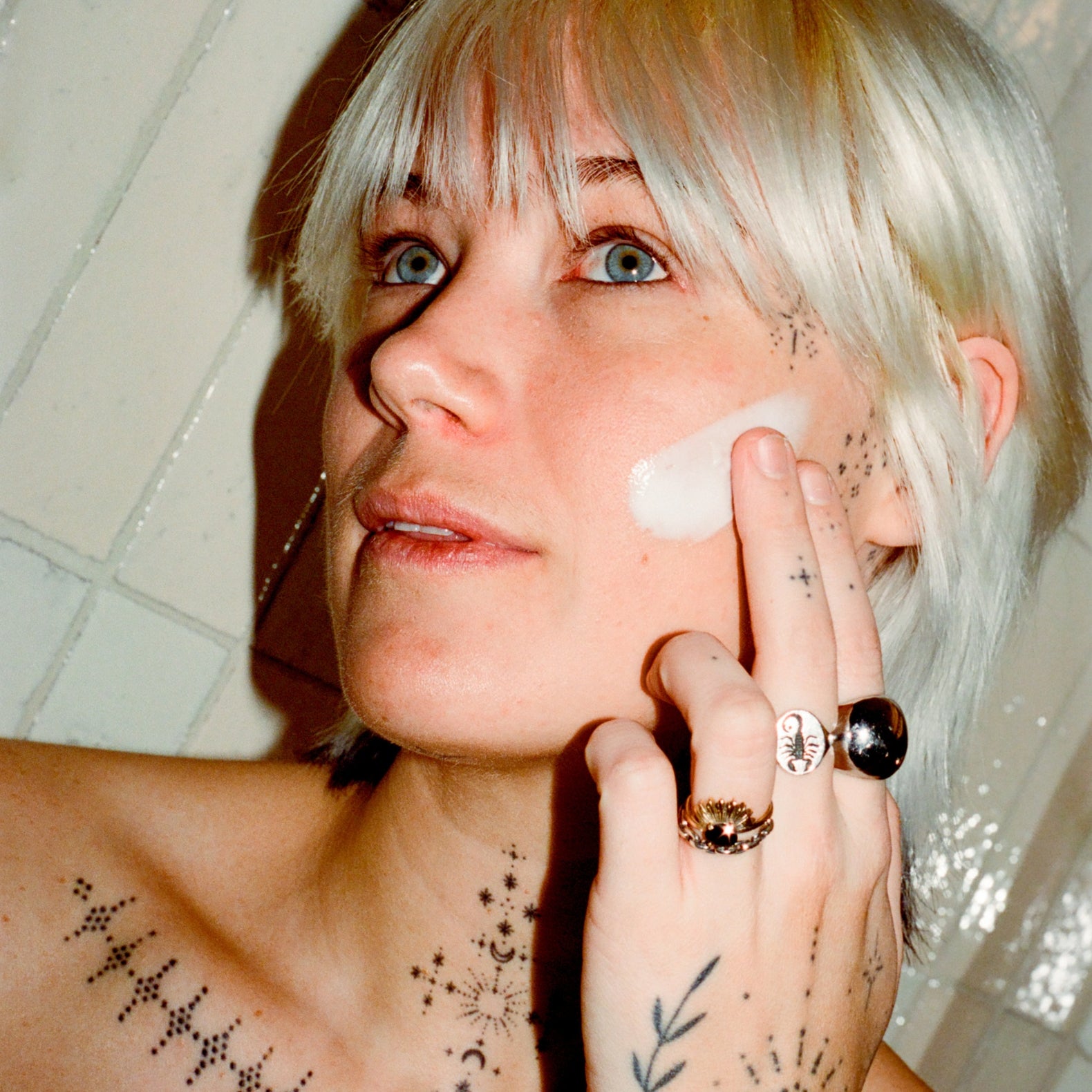 Woman applying 'COMUNE' revitalize overnight mask and night cream to her face with a neutral background