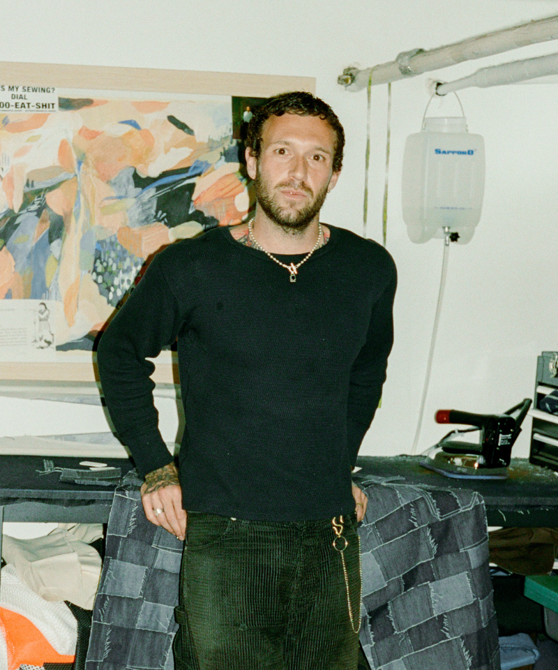 COMUNE artist Jackson Owen standing in a room with denim and iron at his workshop.