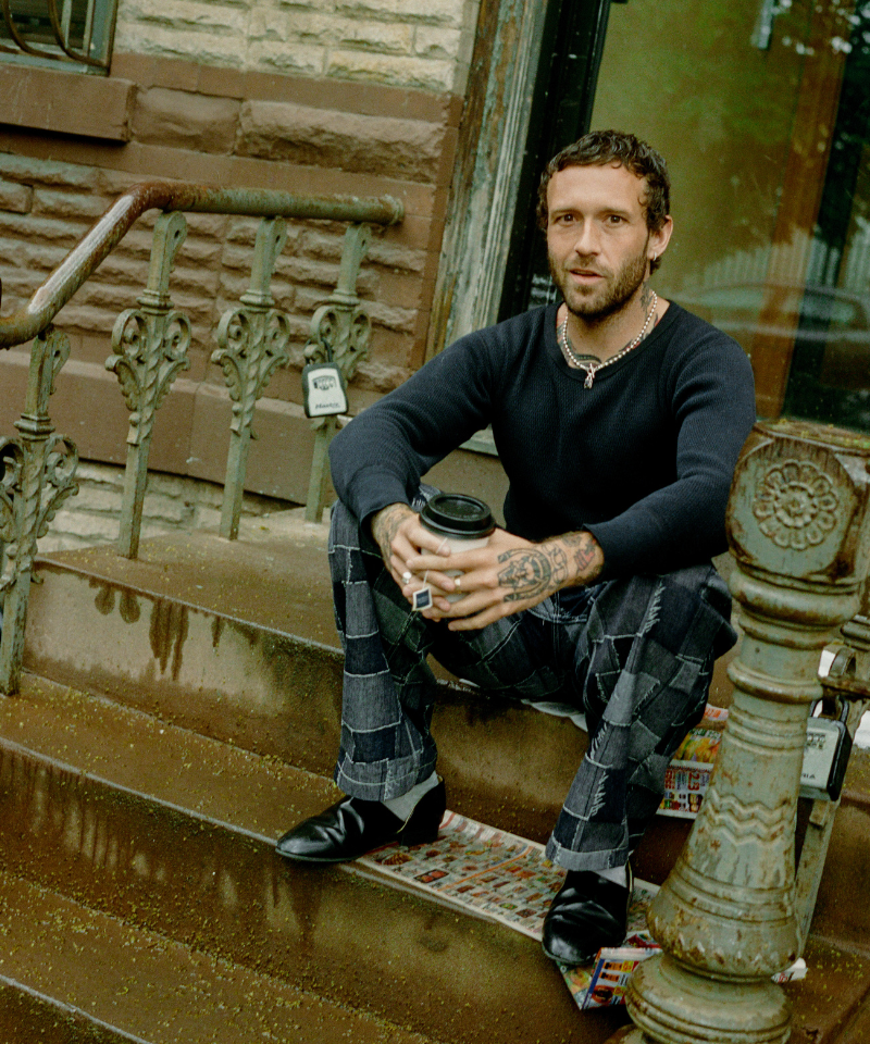 COMUNE Artist Jackson Owens sitting on steps holding coffee
