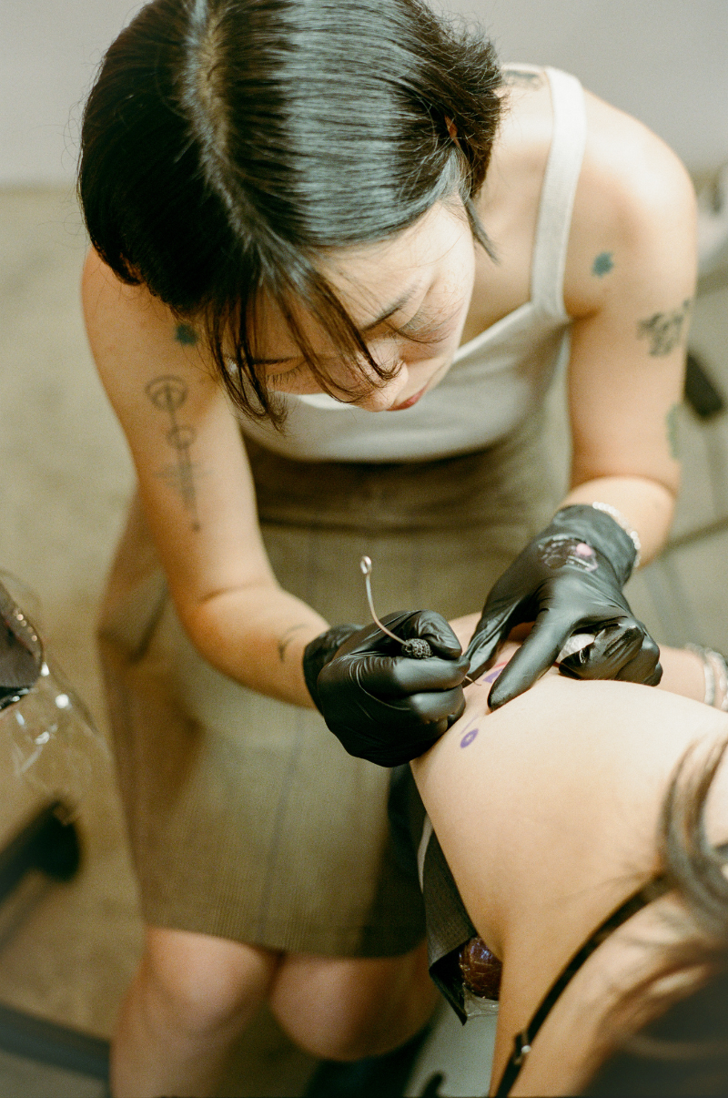 COMUNE artist Odni working her magic by giving a tattoo in a tattoo parlor.