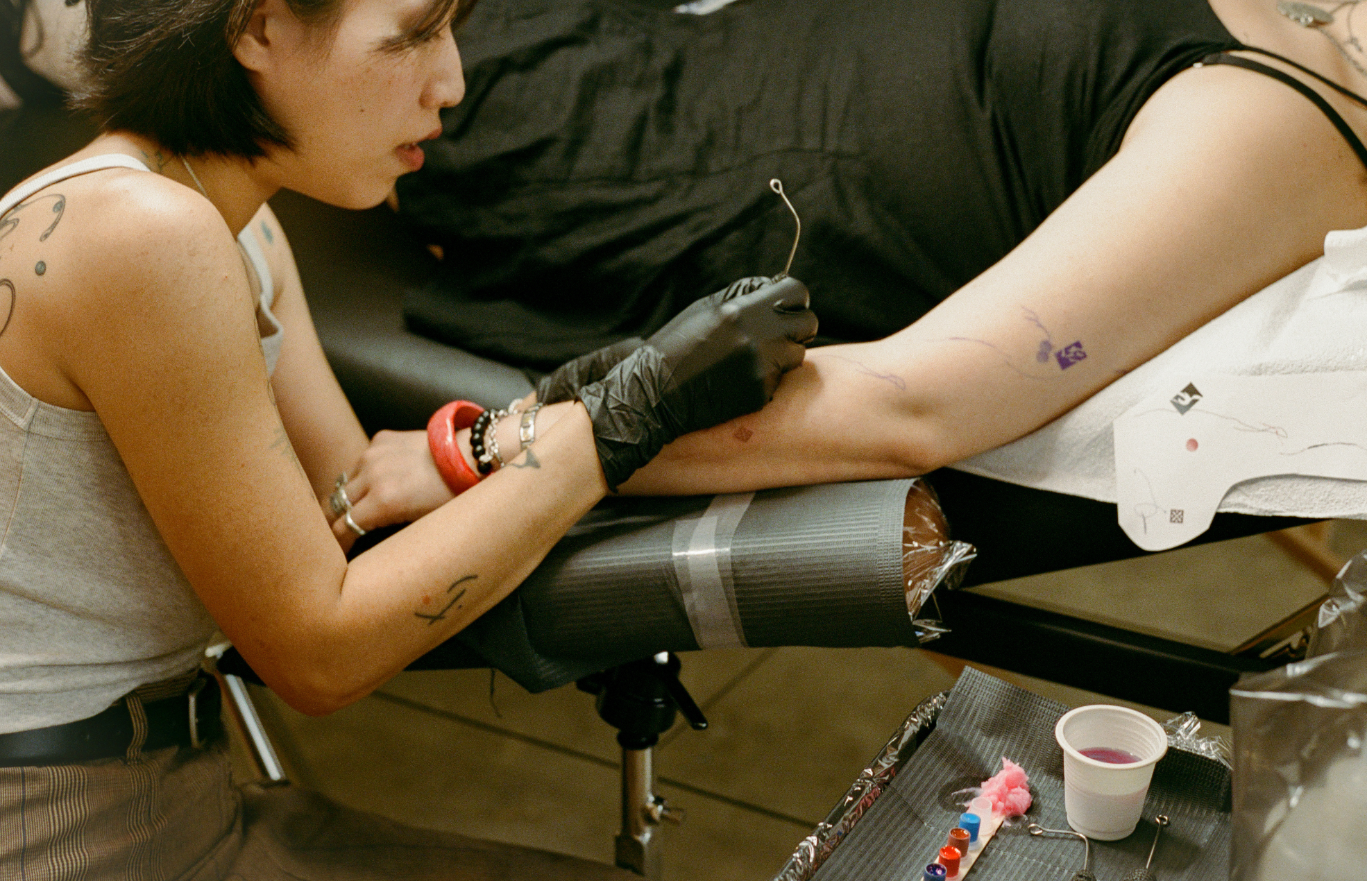 COMUNE artist Odni Lim working with a tattoo machine in a close-up shot.