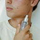 Person holding COMUNE Vita Boost Serum next to his face